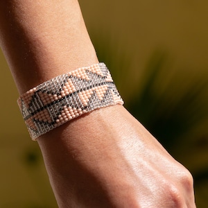 Peut inclure: Un bracelet en perles rose et noir avec un motif géométrique.