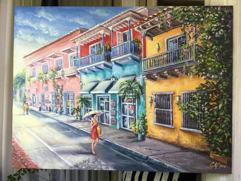 May include: A painting of a colorful street scene in a tropical city. The buildings are painted in shades of pink, yellow, blue, and green. There are balconies with wrought iron railings and lush green plants growing on the walls. A woman in a red dress walks down the street with a yellow umbrella. The sky is blue with white clouds.