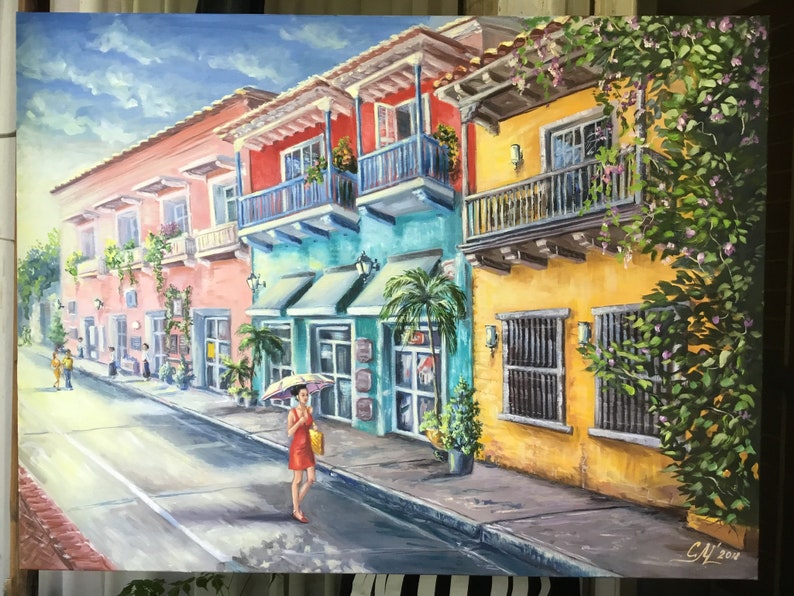 May include: A colorful painting of a street scene in a tropical city. The buildings are painted in bright colors, including pink, yellow, blue, and green. There are balconies with railings and potted plants. A woman in a red dress walks down the street with an umbrella. The street is paved with cobblestones and there is a white line down the center.