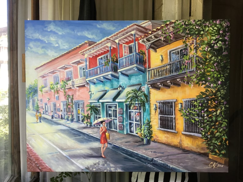 May include: A colorful painting of a street scene in a tropical city. The buildings are painted in bright colors, including yellow, pink, blue, and green. There are balconies with plants and flowers. A woman in a red dress walks down the street with a yellow umbrella. The sky is blue with white clouds.