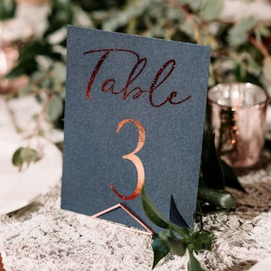 May include: A dark blue table number card with the word "Table" and the number "3" in copper glitter lettering.