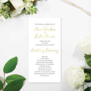May include: Wedding ceremony program with gold lettering on white paper. The program lists the wedding celebration of Anna Dickson and Justin Raines, the date, location, and the order of events.