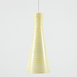 May include: A pale yellow pendant light fixture with a conical shape, featuring a pattern of thin, horizontal white lines. The light hangs from a white cord against a white background. This decorative lighting fixture is suitable for home decor.