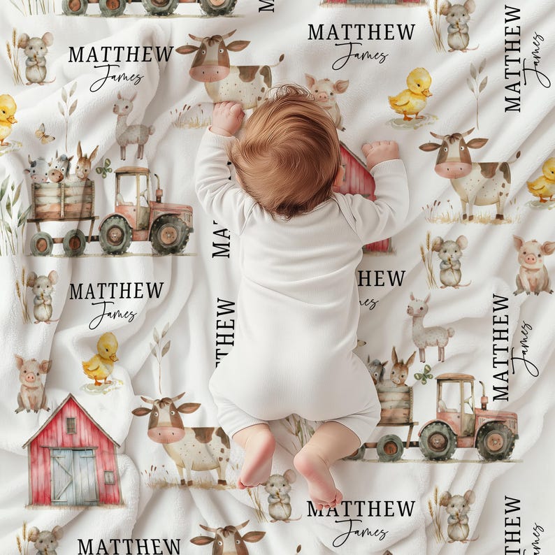 May include: A white baby blanket with a farm animal theme. The blanket features illustrations of cows, pigs, ducks, tractors, and barns. The name "MATTHEW James" is printed repeatedly on the blanket. A baby in a white onesie is lying on the blanket.