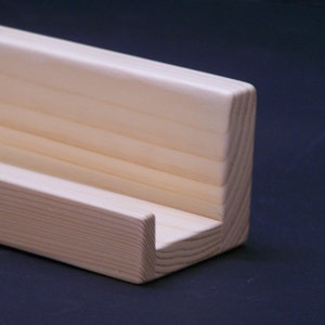May include: A natural wood shelf with a simple design, perfect for displaying small items. The shelf is made of unfinished pine wood and has a natural wood grain.