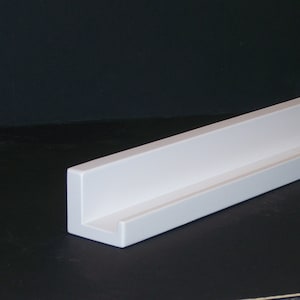 May include: White floating shelf with a simple, modern design. The shelf is made of a sturdy material and has a clean, minimalist look.