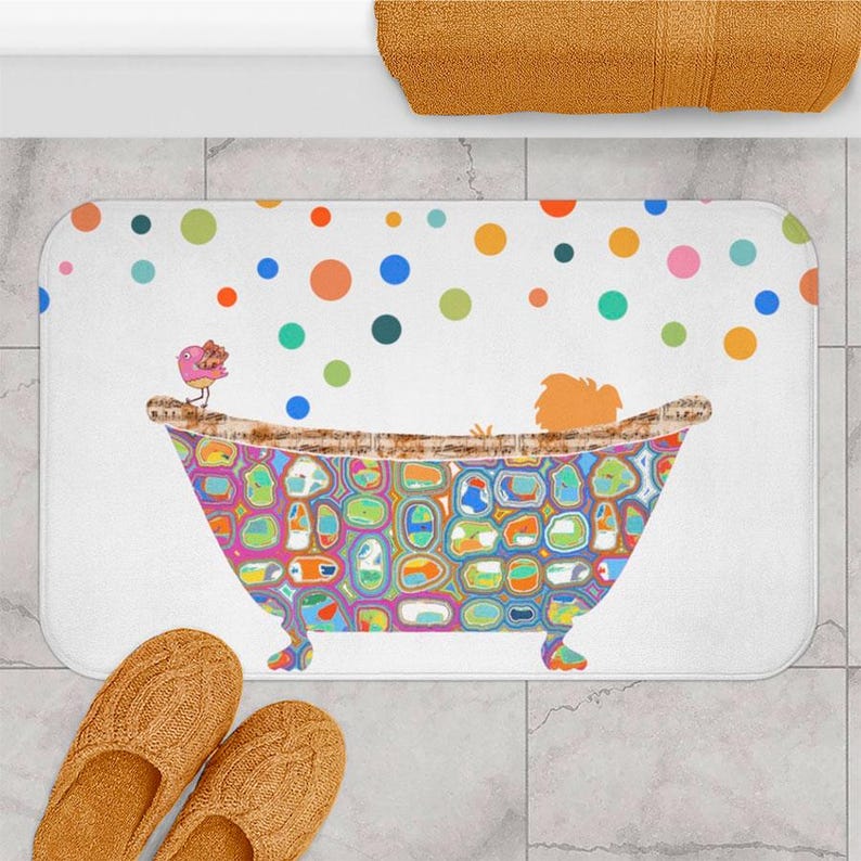 A colorful bath mat with a whimsical illustration of a bathtub filled with bubbles, featuring a bird perched on the edge.