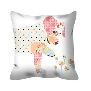 May include: A white pillow with a colorful patchwork puppy design. The puppy is looking down at a cluster of pink, yellow, and orange flowers.