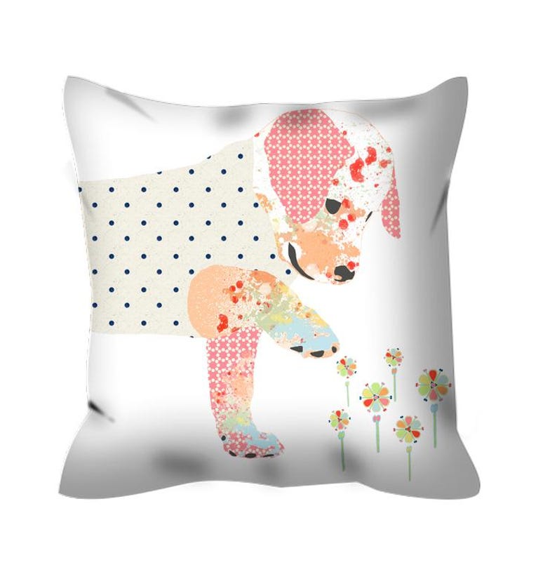 May include: A white pillow with a colorful patchwork puppy design. The puppy is looking down at a cluster of pink, yellow, and orange flowers.