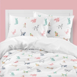 Puede incluir: Juego de cama blanco con un patrón repetido de ilustraciones de gatos coloridos. Los gatos están en varias poses y colores, incluyendo rosa, azul, verde y blanco y negro. El juego incluye una funda nórdica y dos fundas de almohada.