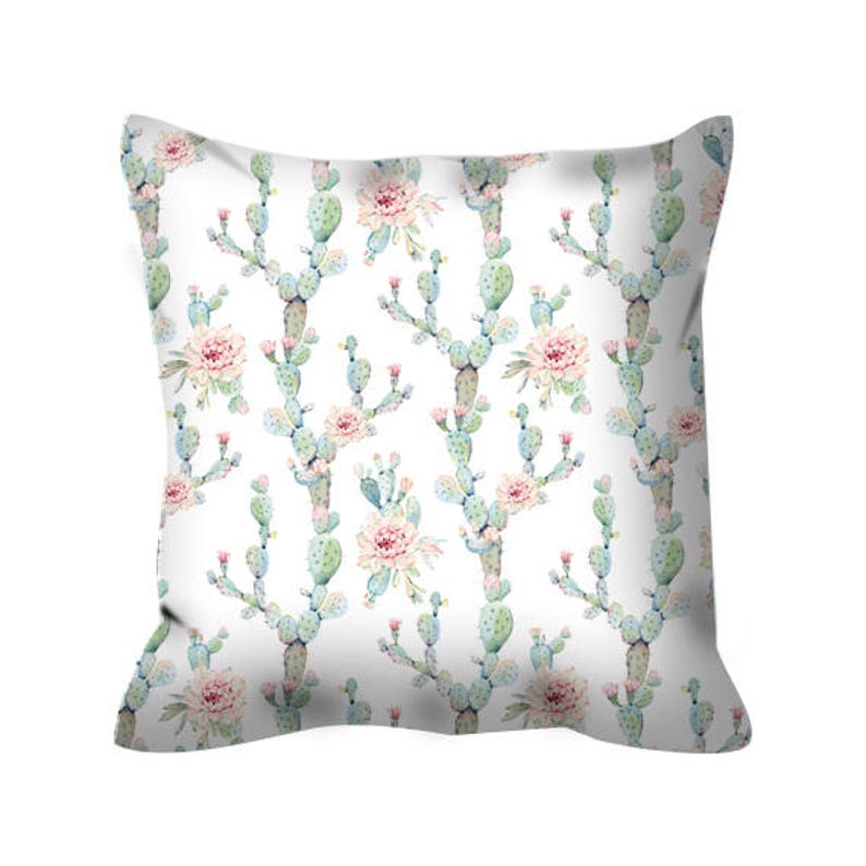 May include: White pillow with a repeating pattern of green cactus plants and pink flowers. The pillow is made of a soft, comfortable fabric and is perfect for adding a touch of nature to your home decor.