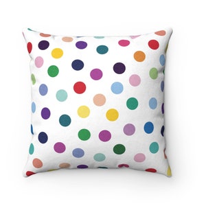 May include: A white throw pillow with a colorful polka dot pattern. The dots are in various shades of red, orange, yellow, green, blue, purple, and pink.