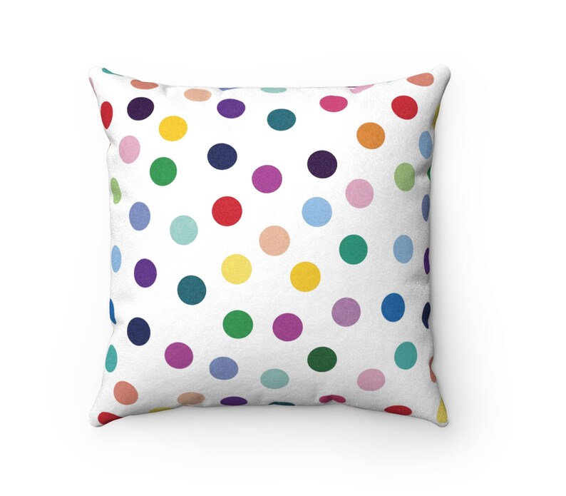 May include: A white throw pillow with a colorful polka dot pattern. The dots are in various shades of red, orange, yellow, green, blue, purple, and pink.