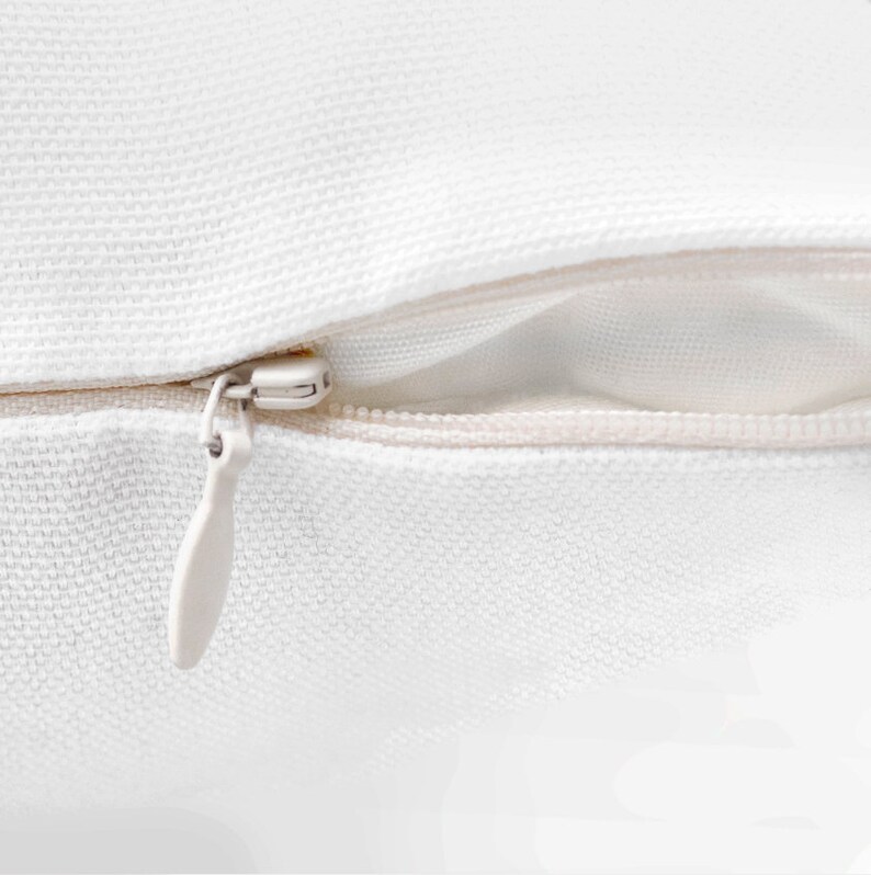 May include: A white zipper closure on a pillow cover. The zipper is made of metal and has a white plastic pull tab.