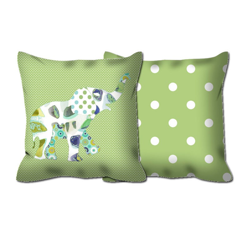 May include: Two green throw pillows, one with a white polka dot pattern and the other with a green polka dot pattern and a colorful patchwork elephant design.