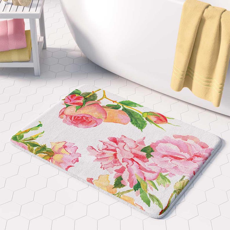 A bathroom with a white bathtub, a yellow towel, and a floral patterned bath mat on the floor.