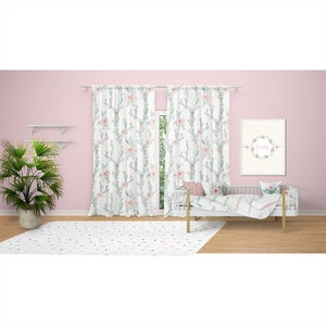 May include: A nursery scene featuring white curtains with a cactus and floral pattern, a white crib with bedding, and a framed print that says "Emily". A white rug with colorful confetti-like shapes is on the floor.