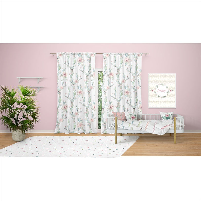 May include: A nursery scene featuring white curtains with a cactus and floral pattern, a white crib with bedding, and a framed print that says "Emily". A white rug with colorful confetti-like shapes is on the floor.