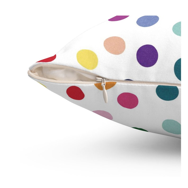 May include: A white pillow with a zipper closure and a colorful polka dot pattern. The dots are in various colors, including red, yellow, blue, green, and purple.