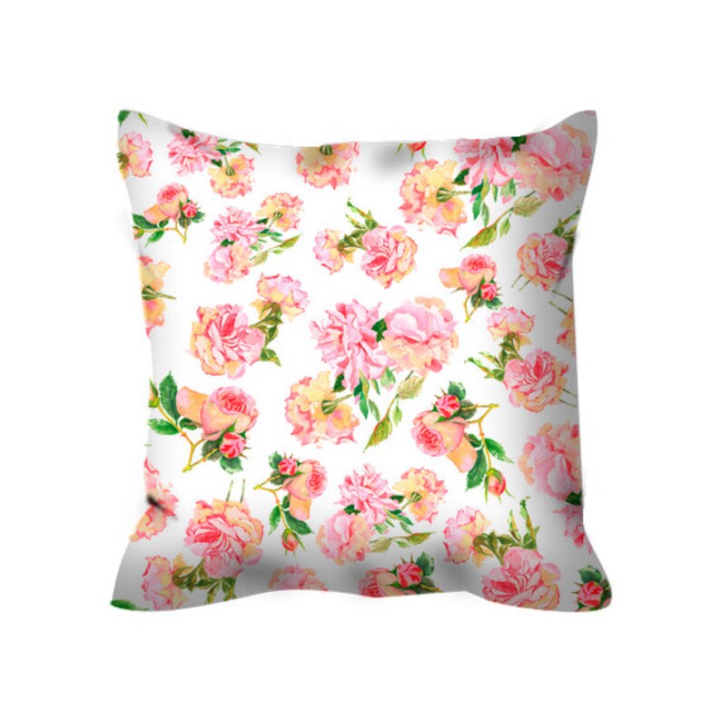 May include: A white pillow with a pink and yellow floral pattern. The pillow features a repeating pattern of roses and other flowers.