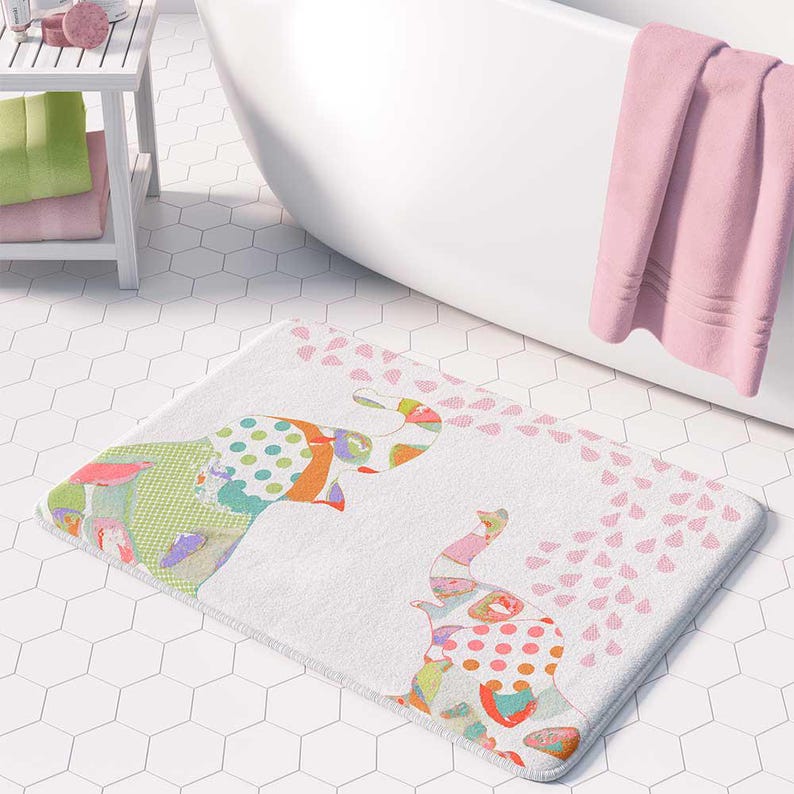 A colorful elephant-themed bath mat with a playful design is placed on a tiled floor in a bathroom.