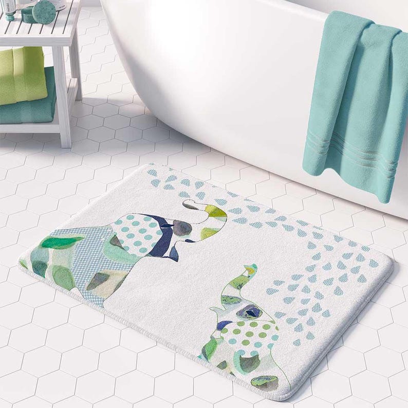 a bathroom with a white bathtub, a colorful elephant-themed bath mat, and a green towel hanging on the side of the bathtub.