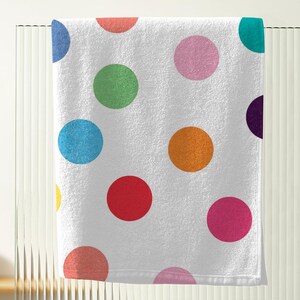 A white towel with a colorful polka dot pattern is hanging on a metal rack.