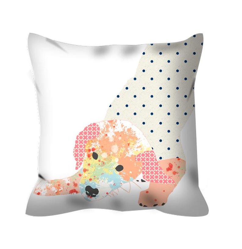 May include: A white pillow with a colorful dog illustration. The dog is painted in shades of pink, orange, yellow, and blue. The dog is wearing a polka dot dress with blue dots on a white background.