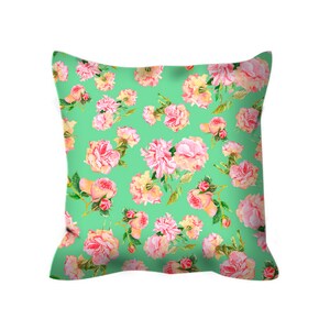 May include: A green pillow with a floral pattern featuring pink and white roses. The pillow is made of a soft, comfortable fabric and is perfect for adding a touch of elegance to any room.
