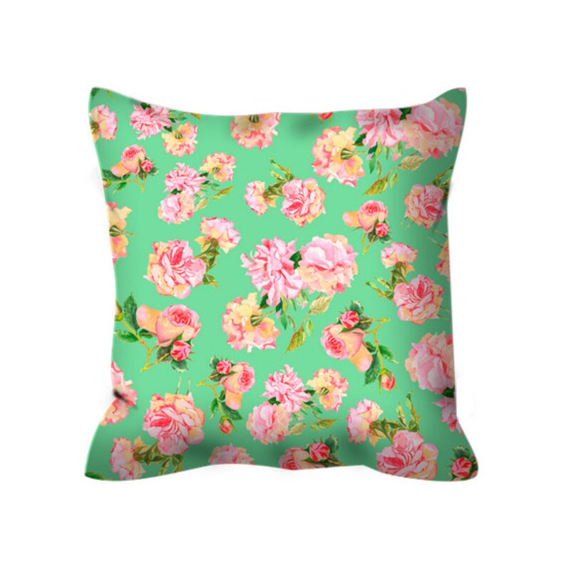 May include: A green pillow with a floral pattern featuring pink and white roses. The pillow is made of a soft, comfortable fabric and is perfect for adding a touch of elegance to any room.