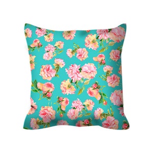 May include: A turquoise pillow with a floral pattern featuring pink and white roses. The pillow is made of a soft, comfortable fabric and is perfect for adding a touch of elegance to any room.