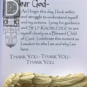 May include: A page from a book with the text "Dear God-" and a prayer. The text is in black script. The bottom of the page shows a sculpted angel wing in a cream color.