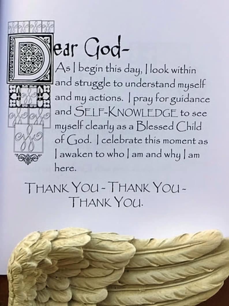 May include: A page from a book with the text "Dear God-" and a prayer. The text is in black script. The bottom of the page shows a sculpted angel wing in a cream color.