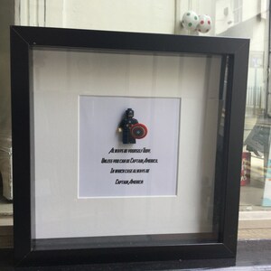 May include: A black framed picture with a white mat and a Lego figurine of Captain America. The quote "ALWAYS BE YOURSELF TOBY, UNLESS YOU CAN BE CAPTAIN AMERICA IN WHICH CASE ALWAYS BE CAPTAIN AMERICA" is printed below the figurine.