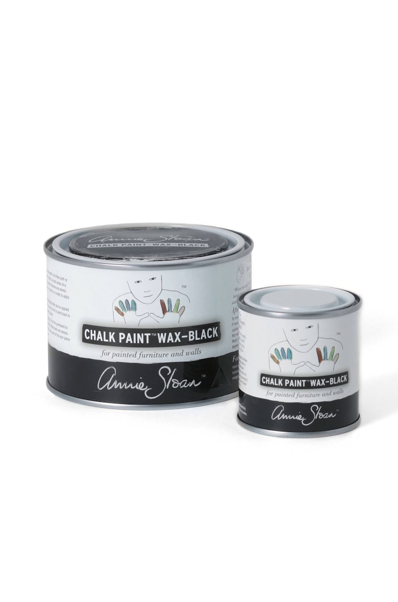 May include: Two cans of Annie Sloan Chalk Paint Wax-Black, one larger and one smaller. The cans are silver with black labels and feature a hand with painted fingers.