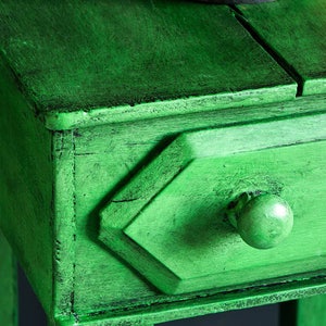 May include: A small green wooden side table with a single drawer and a round knob. The table has a distressed finish and is painted a deep green colour.