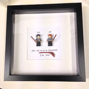 Peut inclure: Une image encadrée avec deux figurines Lego tenant des baguettes magiques. Le texte dit "Jason, Jake, Jake, veux-tu être mon témoin ? Avec amour, Jason".