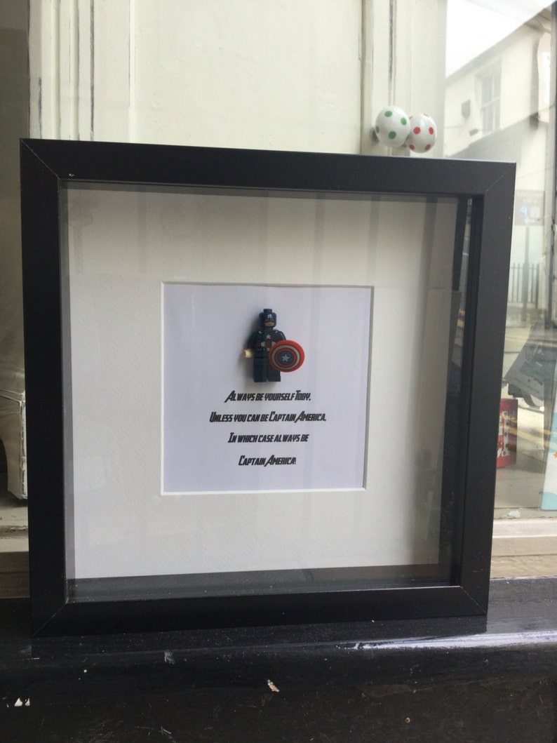 May include: A framed print with a Lego figurine of Captain America holding his shield. The print includes the text "Always be yourself Toby, unless you can be Captain America, in which case always be Captain America."