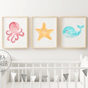 May include: Three watercolor prints featuring a pink octopus, a yellow starfish, and a blue whale. Each print has a white background with small gray dots and is framed in a light wood frame.