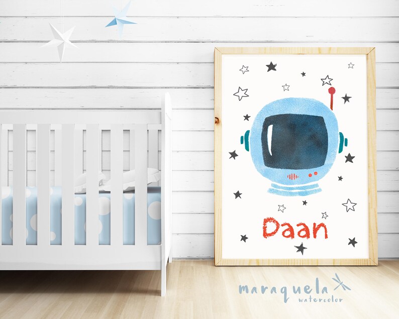 Pu&ograve; includere: Una stampa ad acquerello di un casco da astronauta con stelle e il nome "Daan" in lettere rosse. La stampa &egrave; incorniciata in una cornice di legno chiaro e posizionata su uno sfondo di legno bianco.