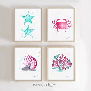 May include: Set of four watercolor prints featuring a pink crab, a coral reef, a nautilus shell, and two starfish. The prints are framed in light wood frames and have a white background with watercolor splatters.