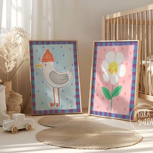 May include: Two framed art prints. One features a cartoon seagull wearing an orange knit cap against a light blue background. The other depicts a smiling daisy on a pink background. Both are in wooden frames with a blue and purple plaid border.