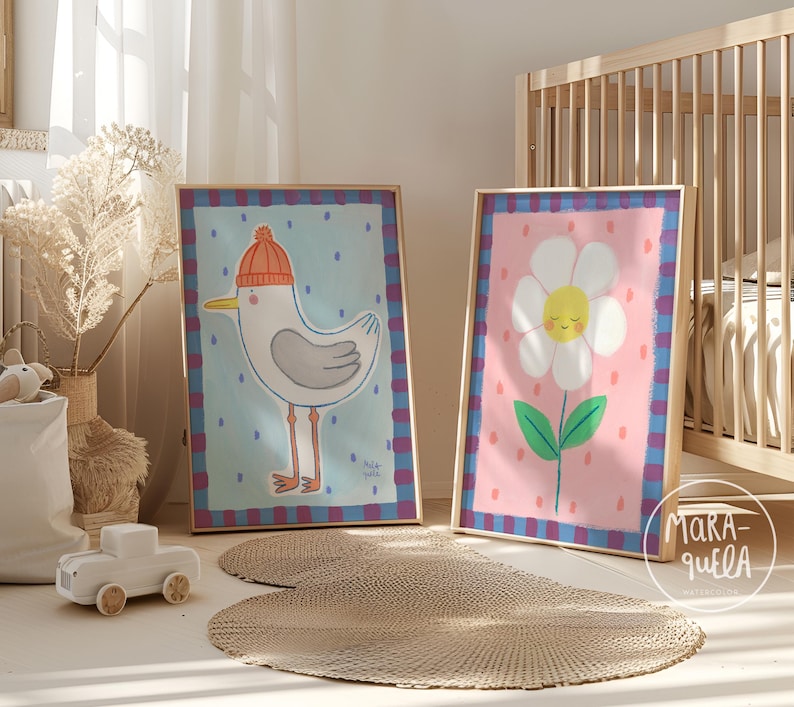 May include: Two framed art prints. One features a cartoon seagull wearing an orange knit cap against a light blue background. The other depicts a smiling daisy on a pink background. Both are in wooden frames with a blue and purple plaid border.