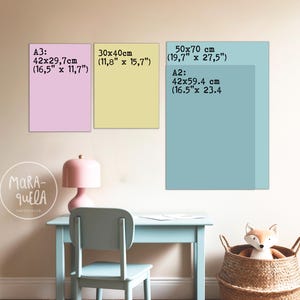 May include: Three rectangular art prints in pastel colors, with size details in inches and centimeters. The prints are displayed above a light blue desk and chair, with a pink lamp and a woven basket containing a stuffed fox. The text "MARA-QUELA WATERCOLOR" is visible.