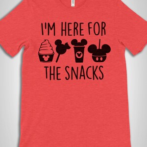 May include: Red t-shirt with the text "I'm here for the snacks" and a row of black Mickey Mouse-themed snacks including a Mickey Mouse ice cream cone, Mickey Mouse lollipop, Mickey Mouse coffee cup, and Mickey Mouse pretzel.