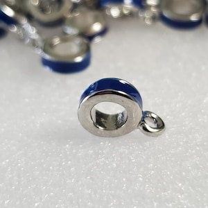 May include: A silver charm with a blue enamel band. The charm has a small loop on the side for attaching to a bracelet or necklace.
