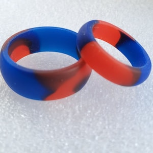 May include: Two silicone rings with a blue and red marbled pattern. The rings are stacked on top of each other.