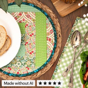 Könnte beinhalten: Ein rundes, gestepptes Platzset mit einem Patchwork-Design aus floralen und einfarbig grünen Stoffbahnen mit sichtbaren weißen Steppnähten. Das Platzset hat einen dunkel-türkisfarbenen Rand und liegt auf einer runden, geflochtenen Unterlage.