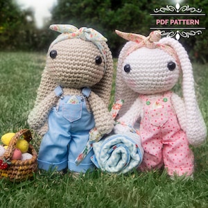May include: Two crocheted bunny dolls with long ears, wearing overalls and floral headbands, stand on grass. One doll wears blue overalls, the other pink with white polka dots. A rolled-up blanket and a basket of Easter eggs are nearby. The image includes the text "PDF PATTERN".