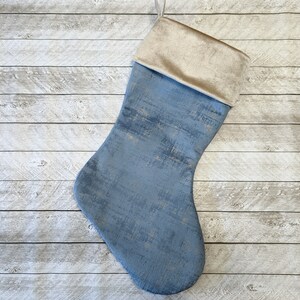 May include: A blue and gold Christmas stocking with a velvet cuff. The stocking has a distressed, textured look.